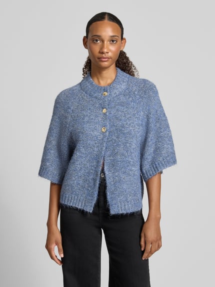 Kobiece modelka nosi Relaxed Fit Cardigan mit Woll-Anteil Modell 'Benutta' od Neo Noir, elastyczna mieszanka materiałów z dodatkiem wełny, imitacja dzianiny, rękaw o dł. 1/2, listwa guzikowa, kolor niebieski, prosta faktura, widok całej sylwetki z przodu.