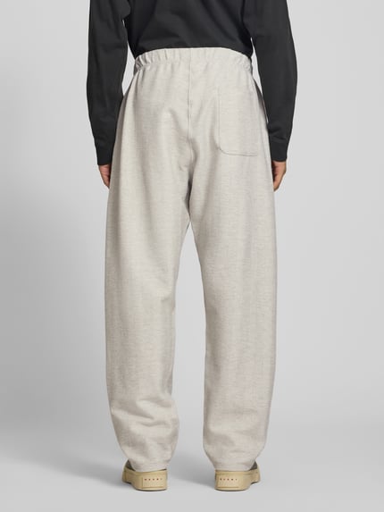 Männermodel trägt Sweatpants aus Baumwoll-Mix von Kenzo in Beige mit elastischem Bund und Label-Print, lockere Passform, Ganzkörperansicht Rückansicht.