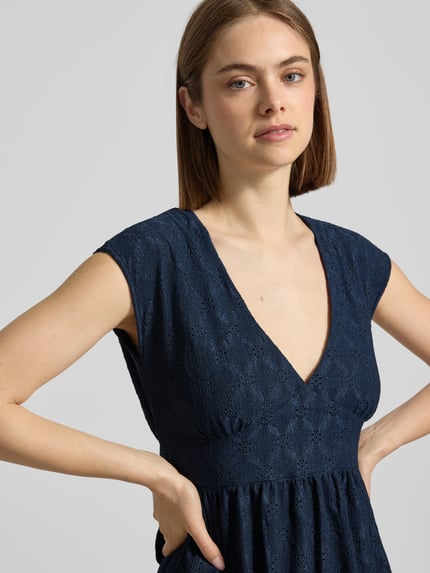 Vrouwenmodel draagt Kurzes Kleid mit V-Ausschnitt, Lochstickerei und großer Schleife van REVIEW in donkerblauw, materiaalmix met stretch, A-lijn, ajourwerk, V-hals, grote strik, ruglengte maat S 84 cm, borstwijdte maat S 42 cm, detailopname bovenlichaam.