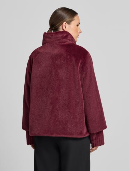 Frauenmodel trägt Jacke mit Stehkragen und gerippten Ärmelabschlüssen von White Label in Bordeauxrot, lockerer Schnitt, Rückenansicht. Kontext: Gerader Schnitt, Stehkragen, verdeckter Verschluss, Rückenlänge 61 cm, Schulterbreite 43 cm, Brustweite 58 cm, Ärmellänge 61 cm.