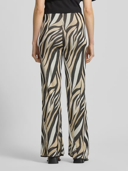 Männermodel trägt Hose aus Viskose im Allover-Look von Marella, wzór na całej powierzchni, pas elastyczny, szerokość w rozmiarze S: 36 cm, długość wewnętrzna nogawki: 84 cm, spodnie z szerokimi nogawkami, widok całej sylwetki od tyłu