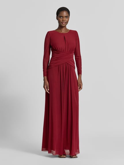 Vrouwenmodel draagt avondjurk met diepe rugdecolleté en plooien van TROYDEN COLLECTION in bordeauxrood chiffon, getailleerd model, ronde hals, druppelvormige hals, semitransparante mouwen, rugritssluiting, ruglengte maat 36: 152 cm, borstwijdte maat 36: 36 cm, mouwlengte maat 36: 58 cm, volledig zicht van voren.