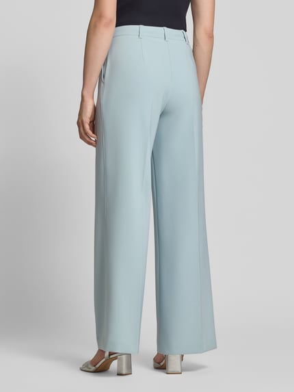 Frauenmodel trägt Wide Leg Hose mit Gürtelschlaufen Modell 'C-TIWI2' von BOSS Orange in Hellblau, glatte Struktur, Ganzkörperansicht Rückansicht.