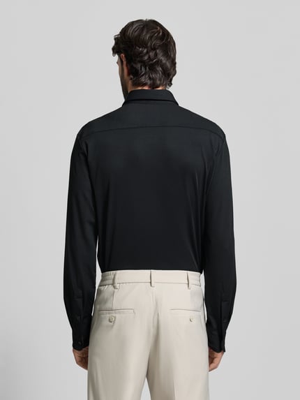 Männermodel trägt Slim Fit Business Hemd mit Kentkragen Modell 'ROAN' von BOSS, unifarben, einreihige Knopfleiste, Ganzkörperansicht Rückansicht.