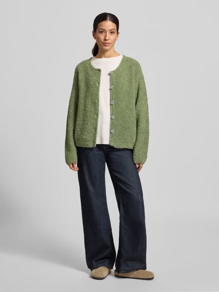 Frauenmodel trägt Strickjacke mit Knopfleiste Modell 'ZOLLY' von American Vintage in Hellgrün, lockerer Schnitt, Lanawoll- und Alpaka-Mix, Ganzkörperansicht von vorne.