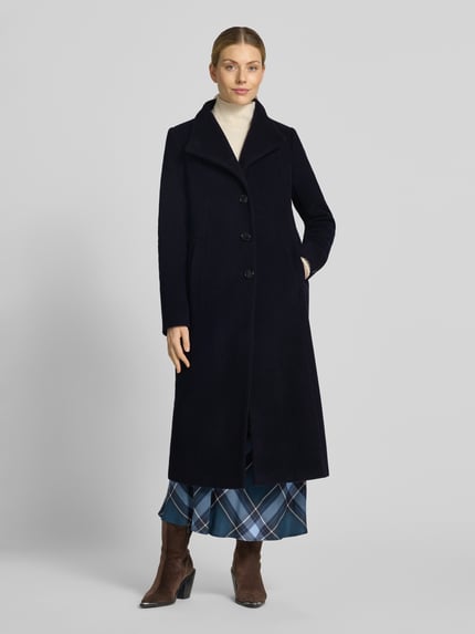 Vrouwenmodel draagt Regular fit lange jas met opstaande kraag Model 'NADA' van Milo Coats, Materiaalmix met scheerwol, knoopsluiting, steekzakken, ruglengte maat 36: 118 cm, schouderbreedte: 40 cm, borstwijdte: 47 cm, mouwlengte: 67 cm, donkerblauw, rechte vorm, zachte textuur, volledig lichaam van voren.