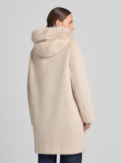 Frauenmodel trägt Mantel aus Kunstfell mit Eingrifftaschen von Marc Cain in Beige, weiche Textur, Rückenansicht, Regular Fit, KI-modifiziertes Bild. Rückenlänge 90 cm, Schulterbreite 39 cm, Brustweite 55 cm, Ärmellänge 63 cm, Knopfverschluss.