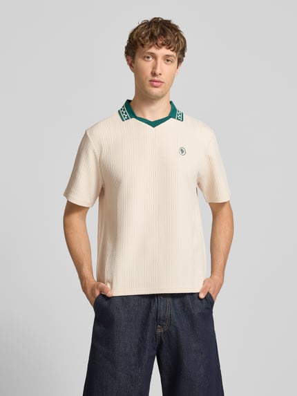 Männermodel trägt Regular Fit Poloshirt mit Logo-Stitching Modell 'Fancy' von REVIEW im Elastischer-Material-Mix, Kurzärmelig, Polokragen, cremefarben mit grünem Kragen, Rückenlänge 87 cm bei Größe M, Ganzkörperansicht von vorne.