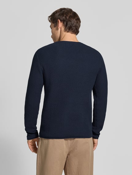 Männermodel trägt Strickpullover mit Struktur-Muster Modell 'BLUMASON' von JACK & JONES aus Baumwolle in Dunkelblau, Ganzkörperansicht Rückansicht.