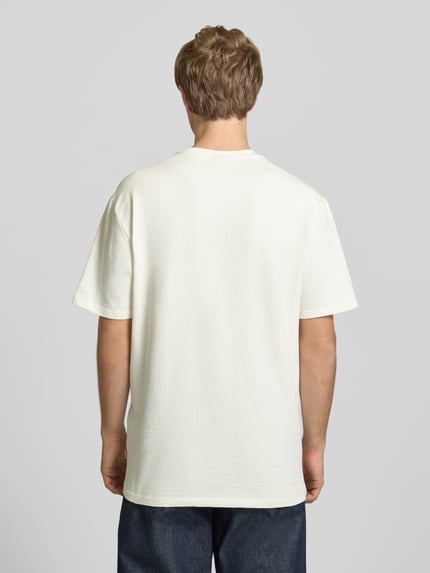 Männermodel trägt Herren T-Shirt Regular Fit T-Shirt aus Baumwoll-Mix Modell 'KIAN' von Only & Sons, Optik: Unifarben, Materialverarbeitung: Piqué, Ganzkörperansicht Rückansicht.