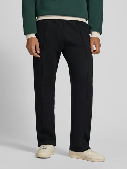 Männermodel trägt schwarze Straight Fit Sweatpants mit elastischem Bund von REVIEW, Material-Mix, Bügelfalte, Nahaufnahme Oberkörper.
