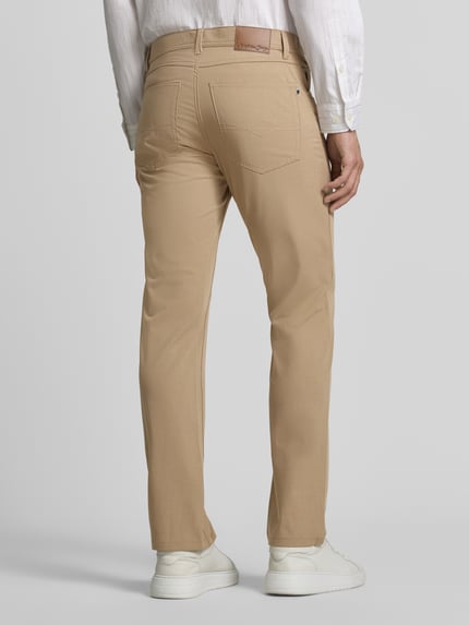 Męski model nosi Comfort Fit Hose mit Eingrifftaschen von Christian Berg Men, beżowe spodnie, mieszanka materiałów z dodatkiem wiskozy, wpuszczane kieszenie, kieszenie z tyłu, szerokość w rozmiarze 32/32: 41 cm, długość wewnętrzna nogawki: 78 cm, całkowity widok z tyłu.