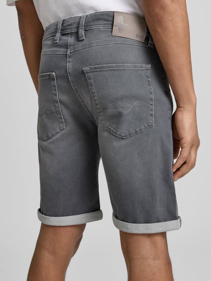 Männermodel trägt Bermudas in Denim-Optik von MAC, Used-Look, Umschlag, Eingrifftaschen, graue Farbe, Ganzkörperansicht Rückansicht.