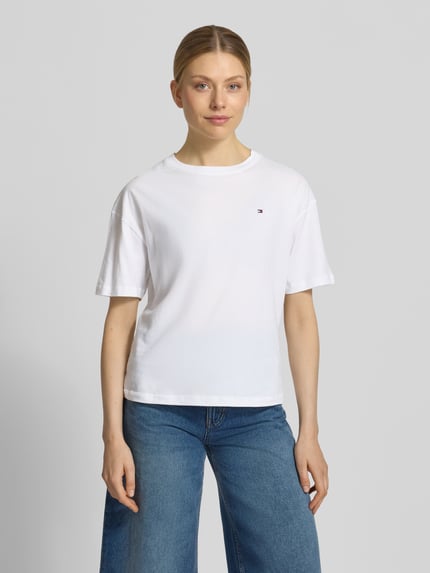 Frauenmodel trägt Slim Fit T-Shirt aus reiner Baumwolle von TOMMY HILFIGER in Optik: Unifarben mit Logo-Stitching, aus Jersey, Nahaufnahme Oberkörper.