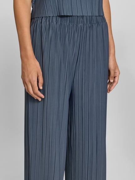 Frauenmodel trägt Wide Fit Stoffhose in Plissee-Optik Modell 'Uma' von Samsøe Samsøe in blauem Elastischer-Material-Mix, Nahaufnahme Oberkörper, Damen Stoffhose, Elastischer Bund, Bundweite 32 cm, Innenbeinlänge 74 cm.