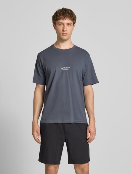 Männermodel trägt Regular Fit T-Shirt mit Logo-Print Modell 'Soho' von Jack & Jones aus reiner Baumwolle in Dunkelgrau, Ganzkörperansicht von vorne. Rückenlänge 61 cm bei Größe M.