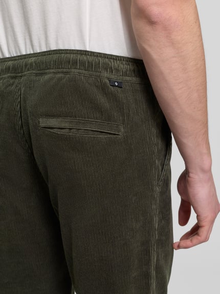 Männermodel trägt Cordhose mit elastischem Bund Modell 'JABARI' von Samsøe Samsøe in Olivgrün, Gesäßtasche, Nahaufnahme Rückansicht, Regular-Fit, Reine Baumwolle, Bundweite 42 cm, Innenbeinlänge 74 cm.