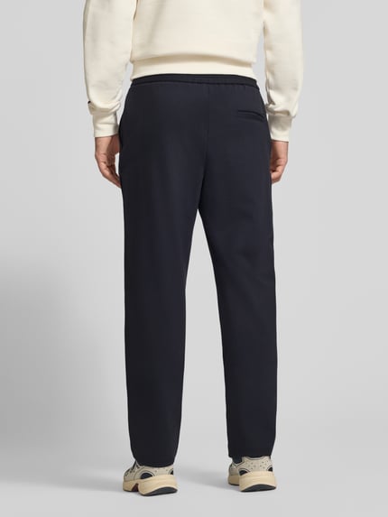 Männermodel trägt Straight Fit aus Viskose-Mix Modell 'Karl' von JACK & JONES in Dunkelblau, elastischer Bund, Ganzkörperansicht Rückansicht. Herren Hose, Bundweite 41 cm, Innenbeinlänge 79 cm.