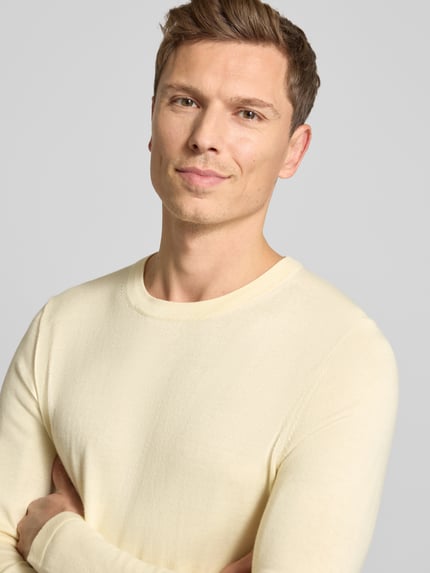 Männermodel trägt Strickpullover mit gerippten Abschlüssen Modell 'Irmino' von Drykorn in Creme, reine Baumwolle, Nahaufnahme Oberkörper.