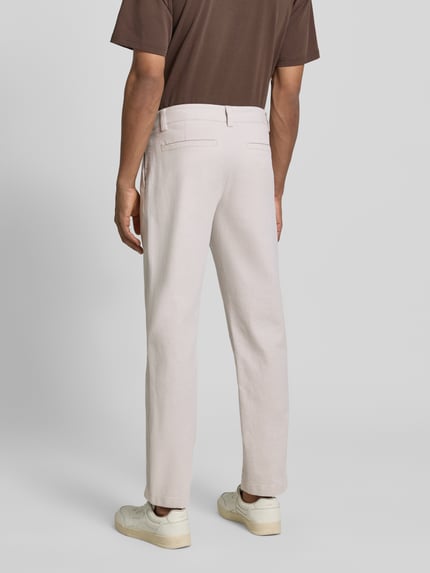 Männermodel trägt Tapered Fit Chino aus Baumwoll-Mix Modell 'CHINO PLEATED' von BOSS Orange, Optik: Unifarben, Materialverarbeitung: Twill, Ganzkörperansicht Rückansicht.