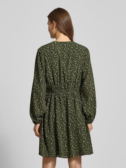 Frauenmodel trägt Minikleid im Allover-Look mit Knopfleiste Modell 'Kaylen Oceanna' von MSCH Copenhagen, A-Linie, grün mit weißen kleinen Mustern, strukturierte Stoffoptik, Rückansicht, Ganzkörperansicht.
