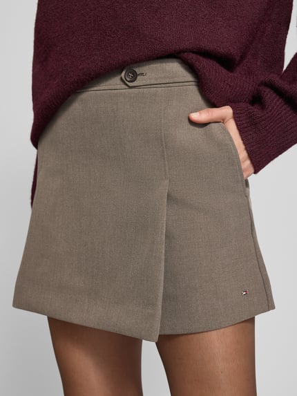 Vrouwenmodel draagt uitlopende mini-rok van viscosemix, uni, met logo-patch en steekzakken, Ausgestellter Mini-Rock aus Viskose-Mix Modell 'PUNTO' van Tommy Hilfiger, Nahaufnahme bovenbenen.