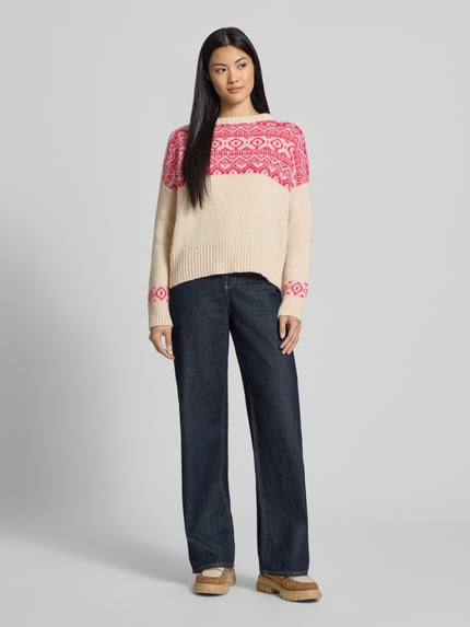 Vrouwenmodel draagt Strickpullover mit Baumwoll-Anteil Modell 'Nordic' van miss goodlife, materiaal-mix, losse fit, staande kraag, geribde boorden, crème met roze patroon, gecombineerd met donkerblauwe jeans, geheellichaamsaanzicht van voren.