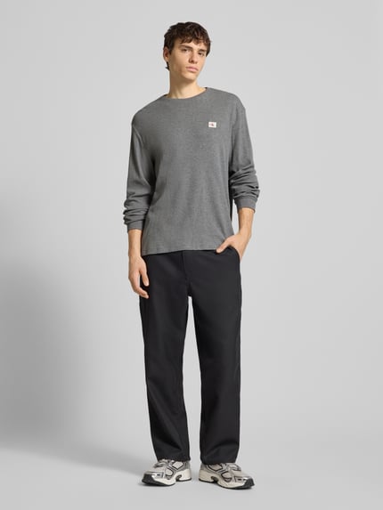 Männermodel trägt Slim Fit Longsleeve mit Logo-Patch Modell 'Waffle' von Calvin Klein Jeans in Grau, Baumwoll-Mix, Piqué, Ganzkörperansicht von vorne.