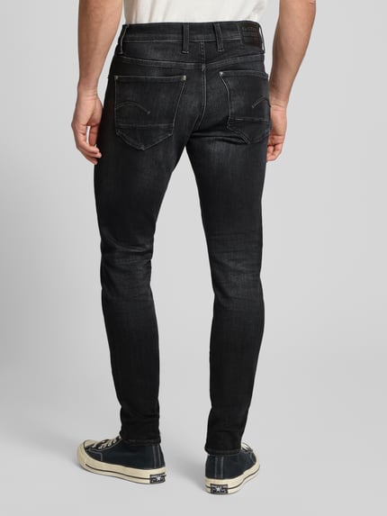Männermodel trägt Skinny Fit Jeans mit 5-Pocket-Design von G-Star Raw in zwart, katoenmengsel met stretch, Ganzkörperansicht Rückansicht.