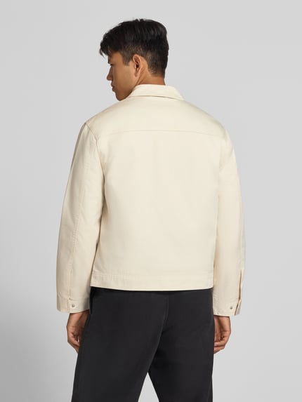 Männermodel trägt Regular Fit Jacke aus Baumwoll-Mix von REVIEW in Beige mit Umlegekragen, Rückenansicht, Ganzkörperansicht Rückansicht. Rückenlänge 66 cm, Schulterbreite 49 cm, Brustweite 56 cm, Ärmellänge 64 cm, Logo-Stitching, Reißverschluss.