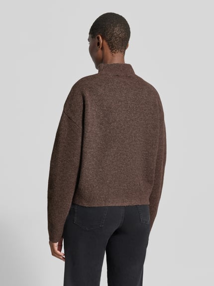 Frauenmodel trägt Turtleneck-Pullover mit Woll-Anteil und Rundhalsausschnitt von Neo Noir in Braun, strukturierte Oberfläche, Ganzkörperansicht Rückansicht. Modell Paulina, gerader Schnitt, überschnittene Schultern, gerippte Abschlüsse.