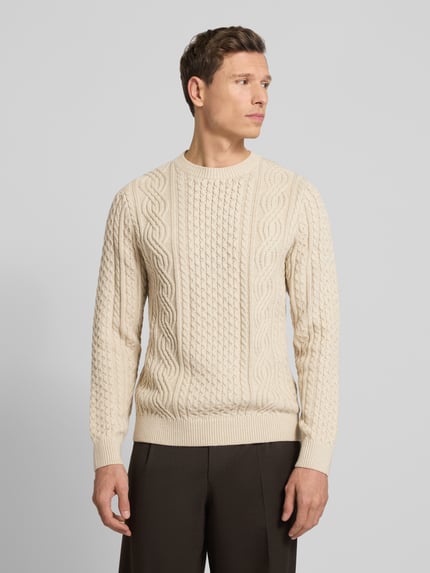 Männermodel draagt gebreide pullover met structuurpatroon, katoenmengsel, regular fit, ronde hals, model 'SEAN' van Jack & Jones Premium, kleur beige. Ganzkörperansicht von vorne.