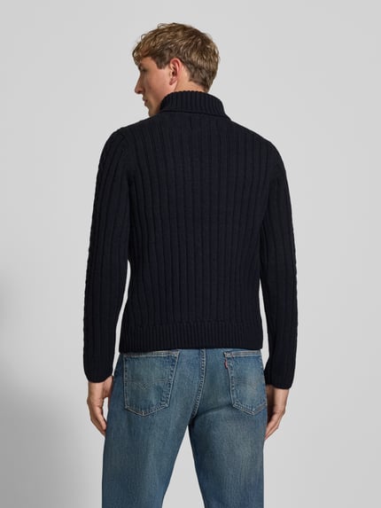 Männermodel trägt Rollkragenpullover mit Zopfmuster von Superdry in Dunkelblau, Slim Fit, Stricktextur, Ganzkörperansicht Rückansicht