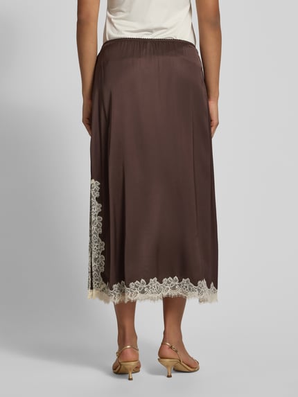Modelka nosi spódnicę midi z wiskozy z obszyciem koronką od Jake*s Collection, linia a, elastyczny pas, brąz i ecru, całkowita długość 86 cm, szerokość w rozmiarze 36: 38 cm, widok na całą sylwetkę z tyłu.