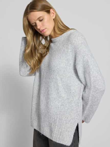 Frauenmodel trägt Pullover mit gerippten Abschlüssen von PIECES in unifarbener Optik, Longline Länge, Rundhalsausschnitt, Nahaufnahme Oberkörper.