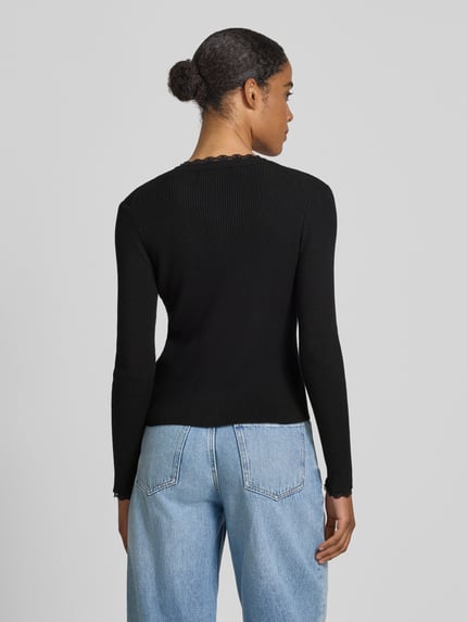 Frauenmodel trägt Slim Fit Strickjacke aus Viskose-Mix Modell 'Wonder' von Vero Moda, Optik: Unifarben, Rippstrick, Ganzkörperansicht Rückansicht.