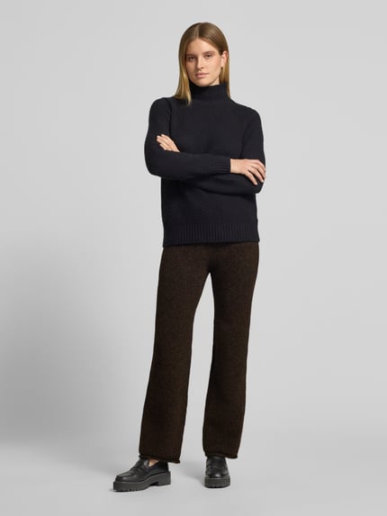 Frauenmodel trägt Hose mit Strickoptik von VERO MODA in Dunkelbraun, weite Form, elastischer Bund mit Tunnelzug, Wollstruktur, Ganzkörperansicht von vorne.