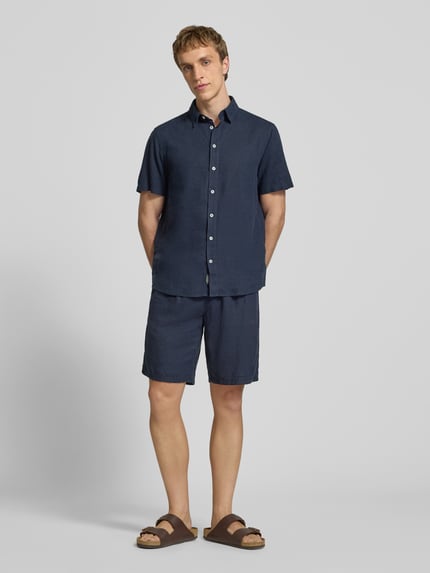 Männermodel trägt dunkelblaues Slim-Fit Leinenhemd mit Viskose-Anteil Modell 'Bobby' von Blend, Kentkragen, Kurzärmelig, Knopfleiste, Ganzkörperansicht von vorne, Rückenlänge 75 cm, Schulterbreite 38 cm, Ärmellänge 23 cm.