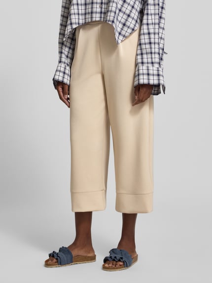Frauenmodel trägt Wide Leg Sweatpants mit Eingrifftaschen von Rich & Royal in Beige, elastischer Bund, Modal-Mix mit Stretch, Nahaufnahme Unterkörper.