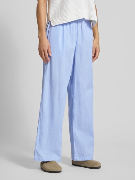 Frauenmodel trägt Loose Fit Weite Hose aus reiner Baumwolle Modell 'AUGUSTA' von Only mit hellblau-weißem Streifenmuster, elastischem Bund und Eingrifftaschen; Ganzkörperansicht von vorne.