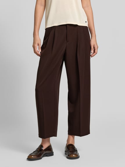 Vrouwenmodel draagt Barrel Fit broek met viscose van s.Oliver RED LABEL in donkerbruin met brede pijpen, detailopname onderlichaam.