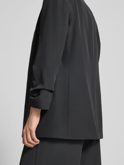 Frauenmodel trägt Relaxed Fit Blazer mit Pattentaschen von Jake*s Collection, Material-Mix mit Stretch, schwarze Farbe, Detailaufnahme Rückansicht.
