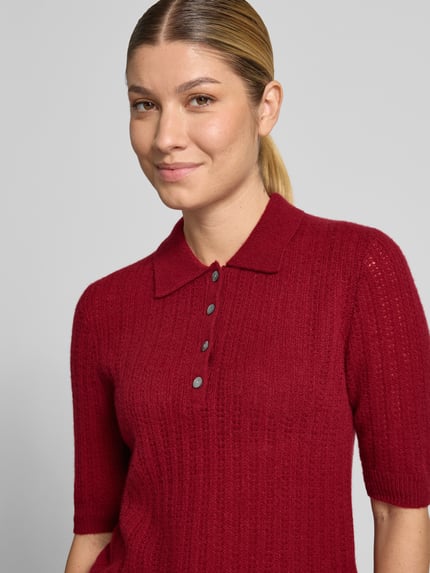 Frauenmodel trägt Slim Fit Poloshirt aus reinem Kaschmir von Christian Berg Woman in Rot, Strick-Optik, kurzärmelig, Nahaufnahme Oberkörper.
