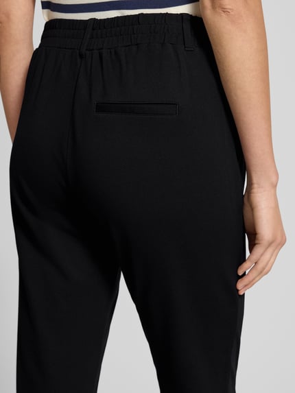 Frauenmodel trägt Easy Pants mit Bundfalten von TOM TAILOR aus schwarzer Viskosemischung mit Stretch-Anteil, Detailaufnahme Rückansicht.