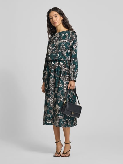 Frauenmodel trägt Cocktailkleid mit Rundhalsausschnitt von Rinascimento im Material-Mix mit Stretch-Anteil, Plisseefalten, dunkel gemustert, körpernahe Passform, Rückenlänge 113 cm, Brustweite 44 cm, Ärmellänge 59 cm, Ganzkörperansicht von vorne.