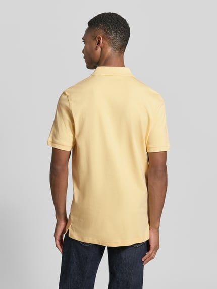 Männermodel trägt Regular Fit Poloshirt mit Logo-Stitching von Fynch-Hatton in Gelb aus reiner Baumwolle, Rückenansicht Ganzkörperansicht.
