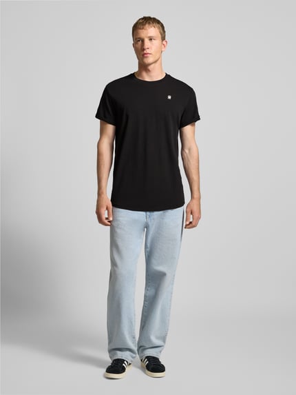 Männermodel trägt T-Shirt mit Label-Detail von G-Star Raw aus reiner Bio-Baumwolle im Gerader-Schnitt, Rundhalsausschnitt, Ganzkörperansicht von vorne.