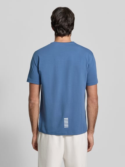 Männermodel trägt Regular Fit T-Shirt mit Logo-Print von EA7 Emporio Armani aus elastischem Baumwoll-Mix, Rückenlänge 66 cm, Ganzkörperansicht Rückansicht.
