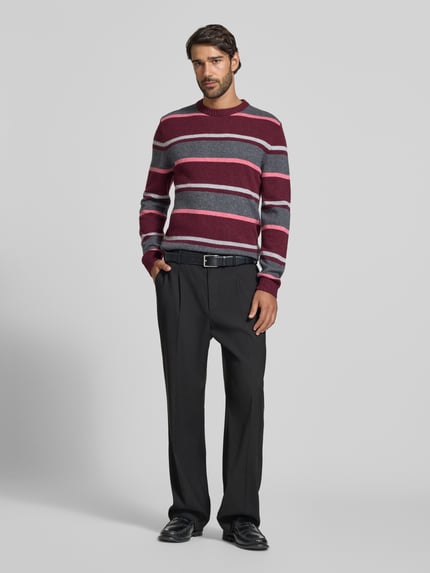 Männermodel trägt Strickpullover aus Woll-Mix im Allover-Look von MCNEAL, Slim Fit, Rundhalsausschnitt, rot-grau gestreift, Ganzkörperansicht von vorne. Rückenlänge 68 cm, Ärmellänge 68 cm.