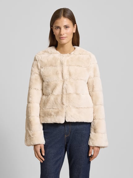 Frauenmodel trägt Jacke aus sztucznego futra z okrągłym dekoltem od More & More, krój regular fit, pikowanie, kremowy kolor, widok z przodu, Ganzkörperansicht von vorne. Długość tyłu 53 cm, szerokość ramion 40 cm, szerokość klatki piersiowej 47 cm, długość rękawów 61 cm, rozmiar 36.